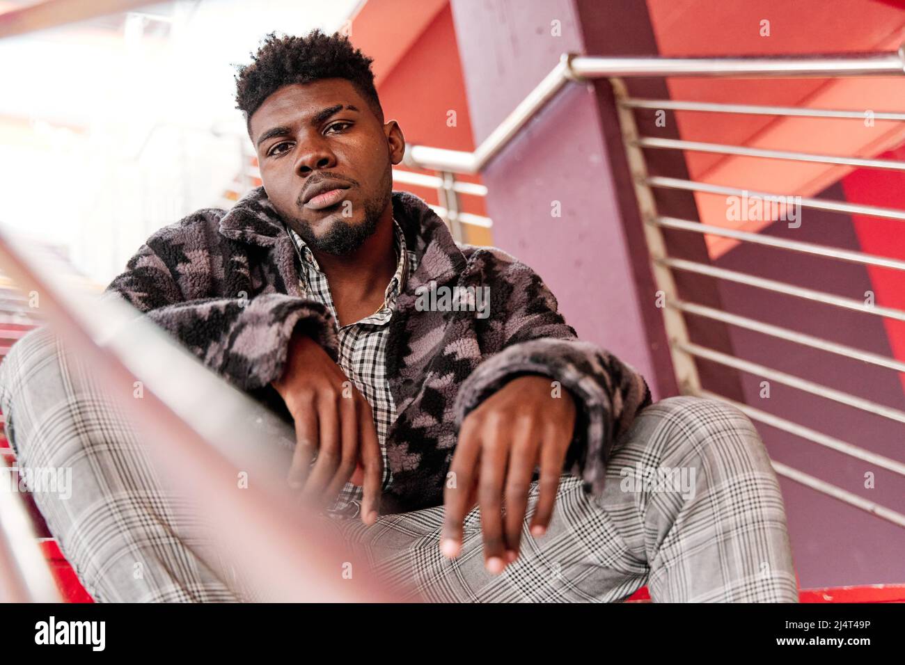 Giovane e attraente uomo studente è seduto sulle scale in città. Foto Stock