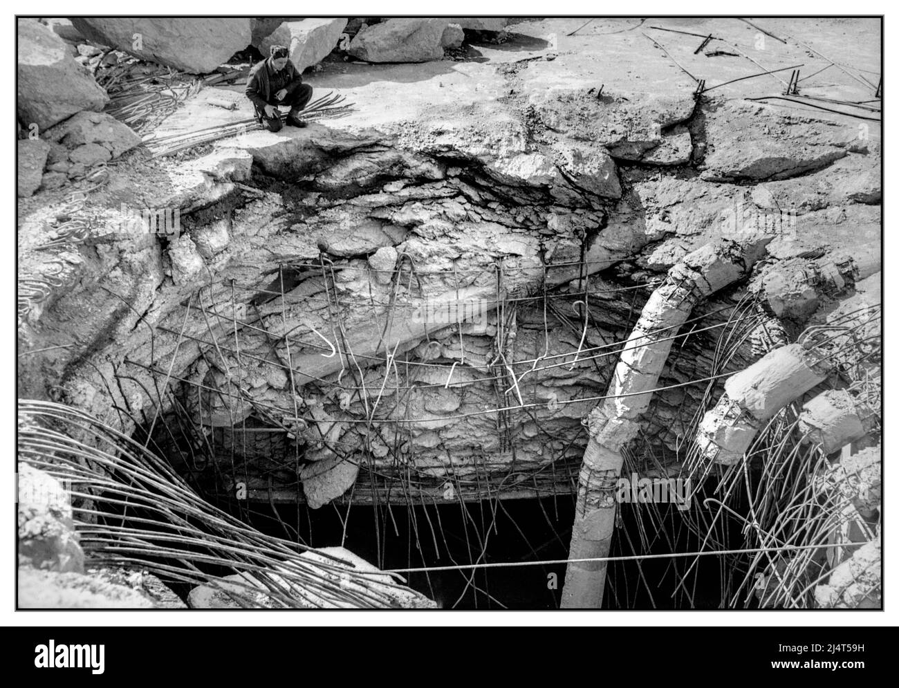 WW2 Penne sottomarine naziste Bremen Germania Royal Air Force Bomber Command, 1942-1945. Un ufficiale della RAF ispeziona il buco lasciato da una bomba "Grand Slam" da 22.000 lb a penetrazione profonda, che ha trafitto il tetto in cemento armato delle penne sottomarine tedesche a Farge, a nord di Brema; Germania: Questo è stato il risultato di un raid alla luce del giorno montato da 18 Avro Lancasters del No. 617 Squadron RAF il 27 marzo 1945, in cui due colpi diretti da 'Grand Slams' causarono il crollo di gran parte del tetto parzialmente completato. Foto Stock