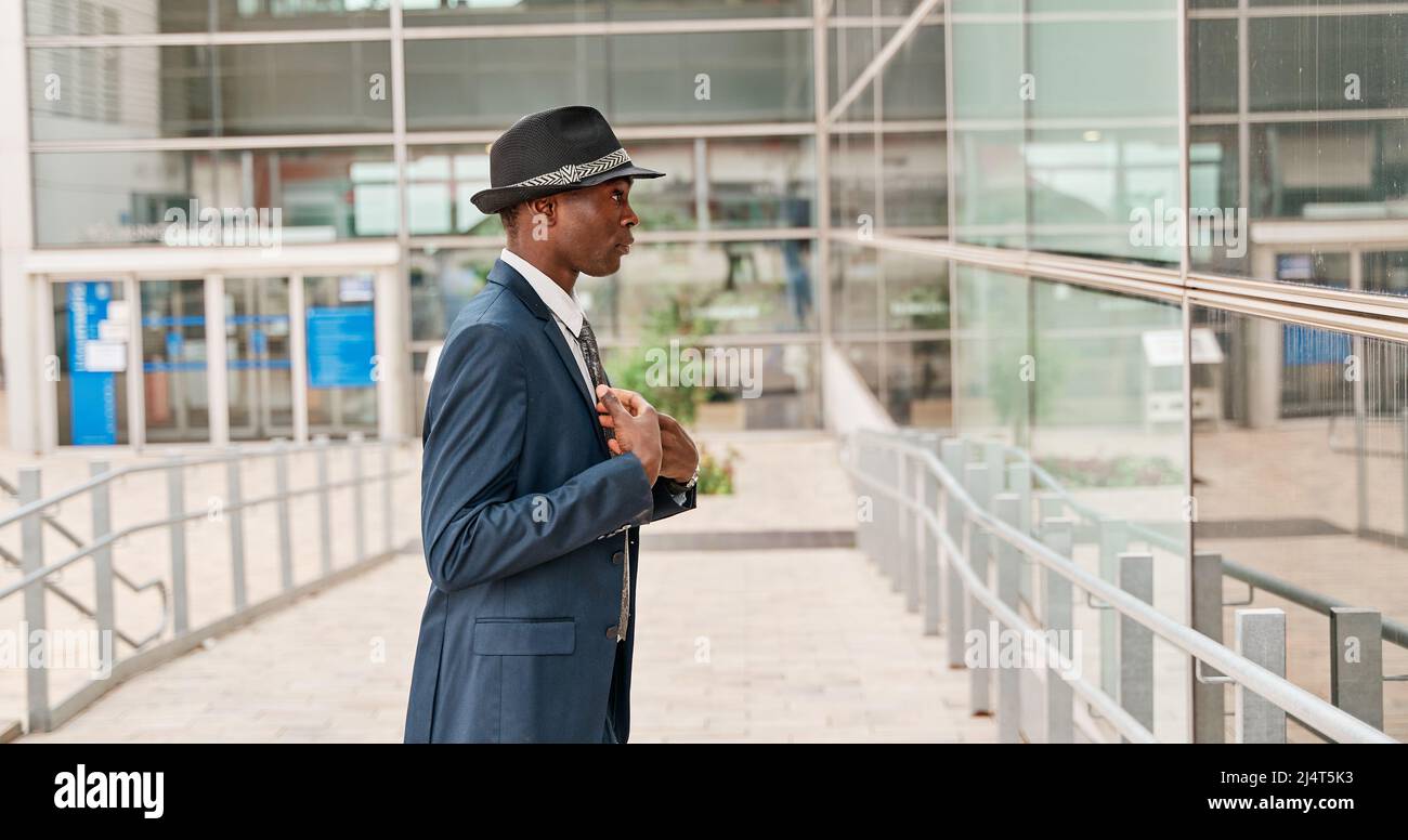 ritratto di un uomo afroamericano in un vestito e cappello guardando in un negozio finestra mettere sul suo vestito. concetto uomo d'affari. Foto Stock