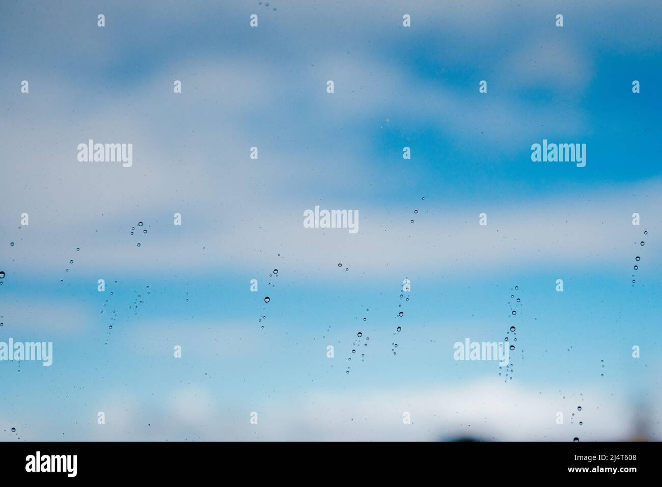 Pioggia su una finestra contro il cielo blu con le nuvole Foto Stock