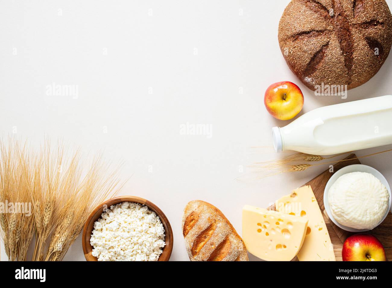 Vacanza ebraica concetto Shavuot. Formaggio casolare di posa piatto, bottiglia di latte, grano, pane di cereali, formaggio, mele su sfondo bianco. Foto Stock