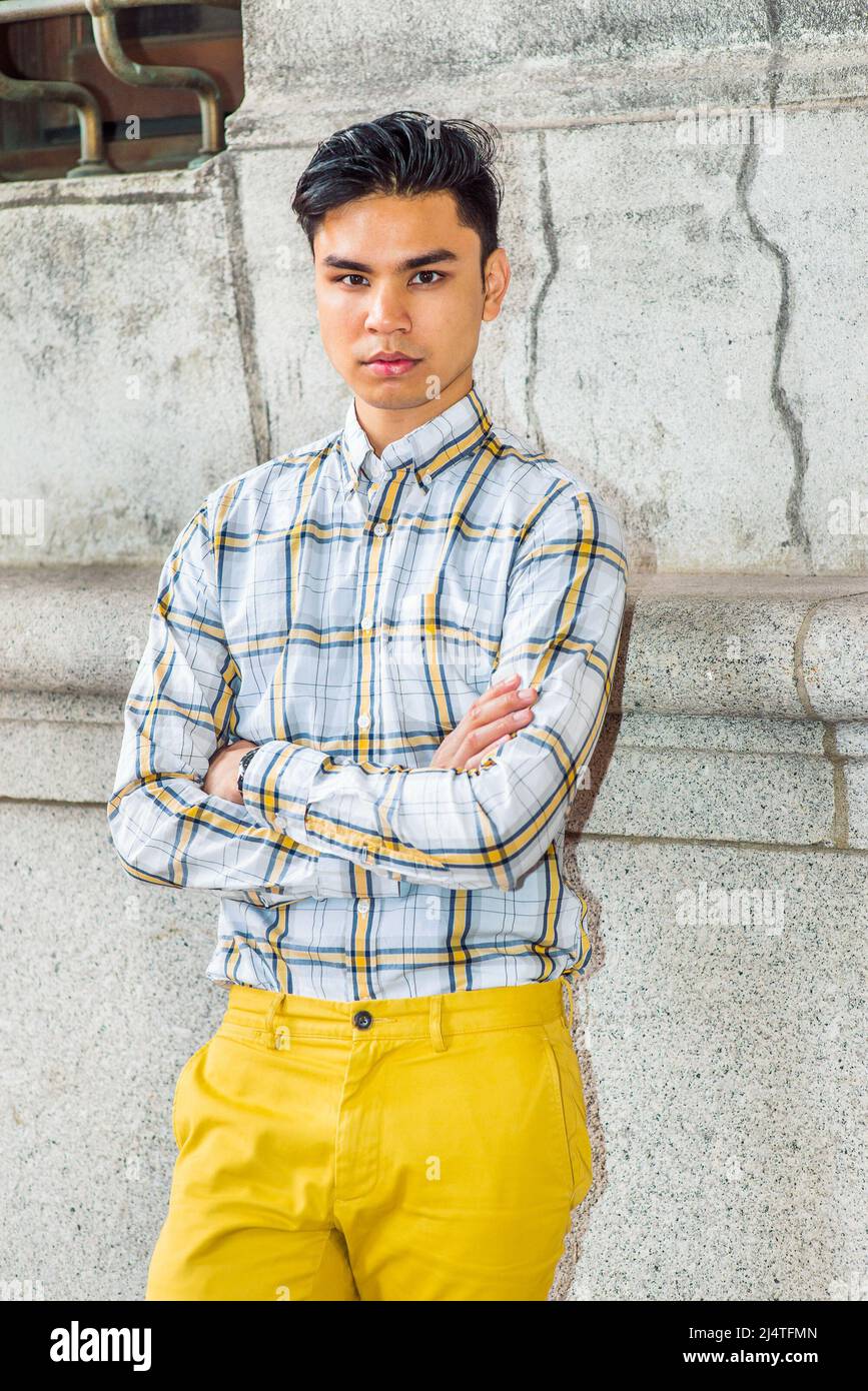 Ritratto di City Boy. Indossando giallo e bianco, camicia a motivi geometrici, pantaloni gialli, braccia incrociate, un giovane ragazzo bello è in piedi da vecchio stile di moda w Foto Stock