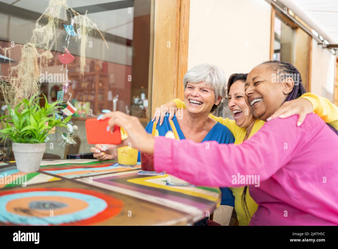 Felice multirazziale anziani amici fare videochiamata con il telefono cellulare al brunch ristorante - anziani generazione tecnologia concetto Foto Stock