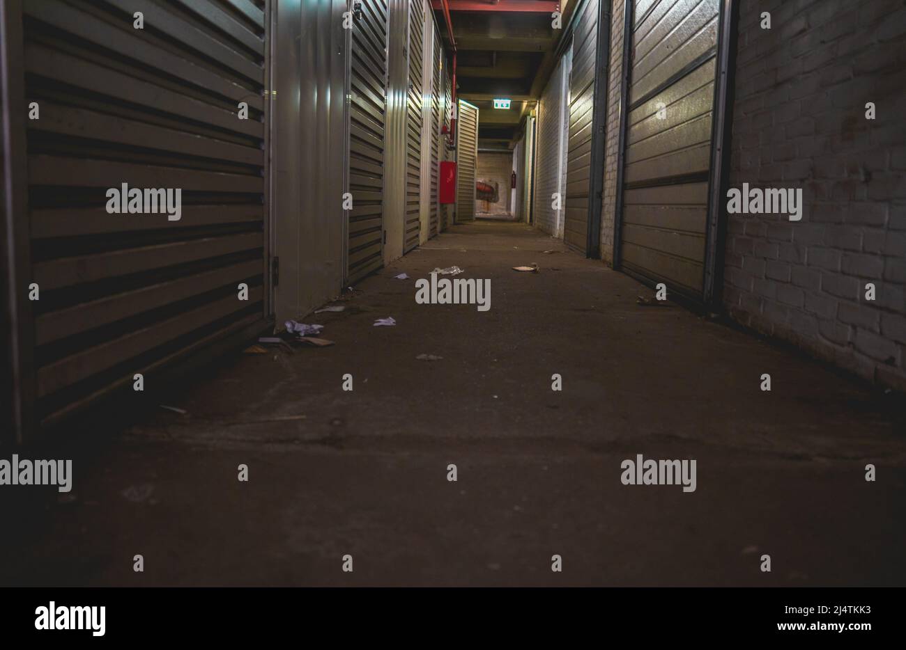 Lungo corridoio scuro con porte per lo stoccaggio in un magazzino Foto Stock