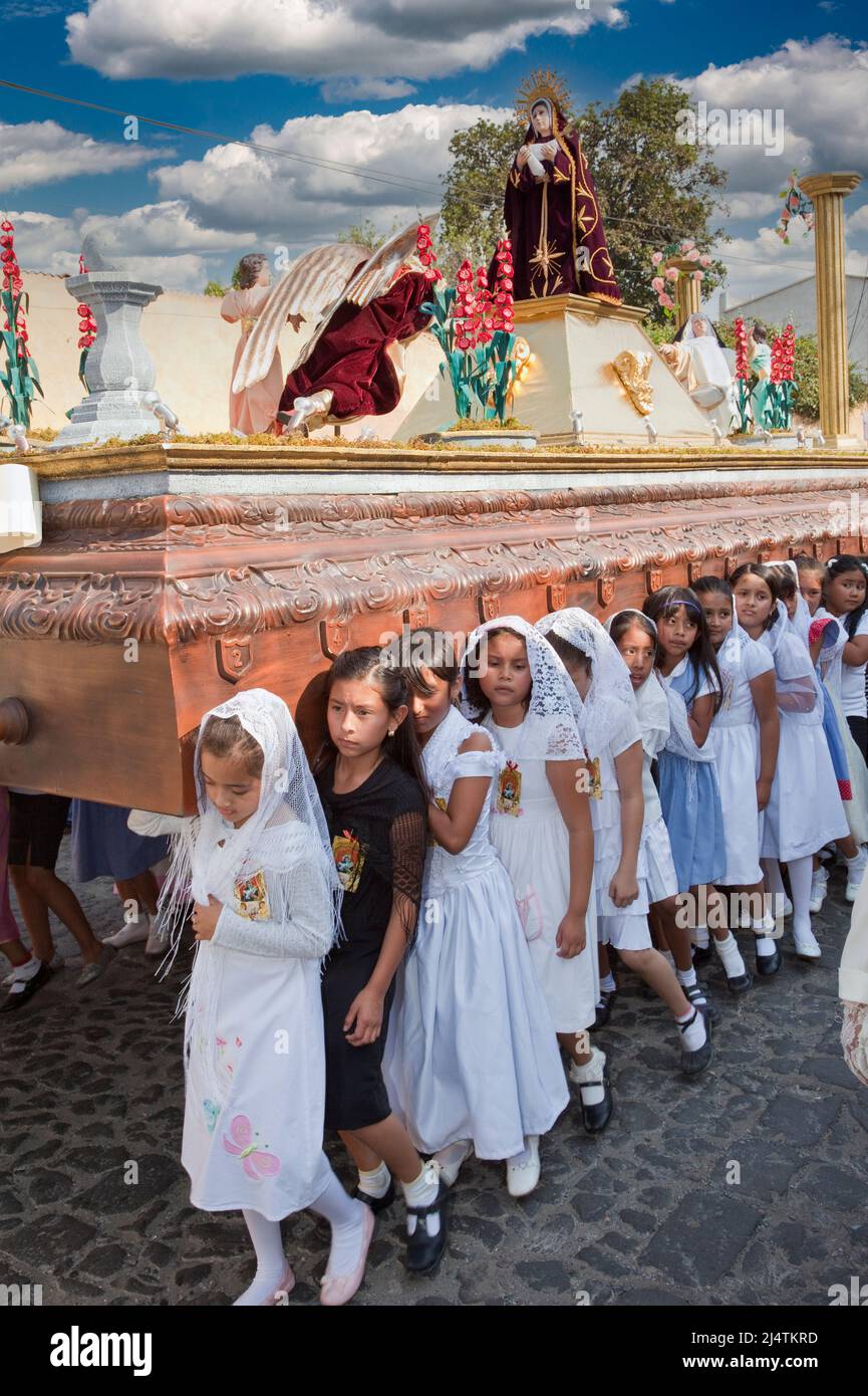 Antigua, Guatemala. Semana Santa (settimana Santa). Giovani ragazze che portano un'Anda (float) con la Vergine Maria in una processione religiosa. Foto Stock