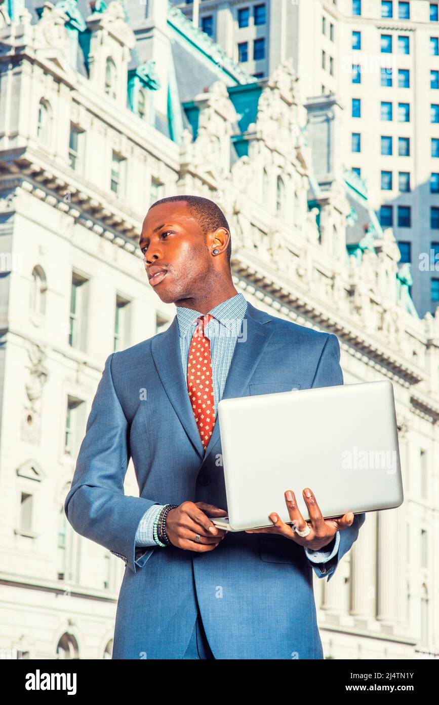 Uomo d'affari che lavora su strada. Vestirsi formalmente in abito blu, sottintagliato a motivi geometrici, cravatta, taglio corto, un giovane ragazzo nero è in piedi in un business d Foto Stock