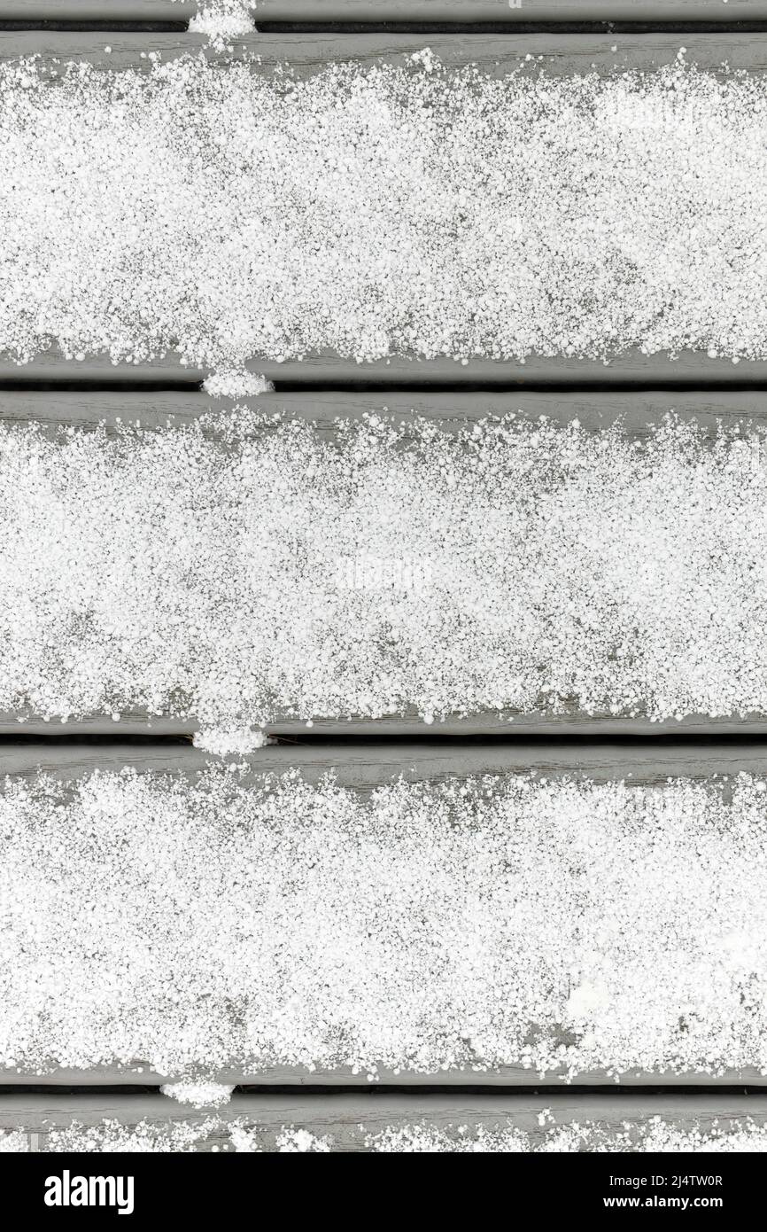 Full Frame Flatlay di Un sottile strato fresco di Graupel Snow sulle tavole Grey Deck Foto Stock