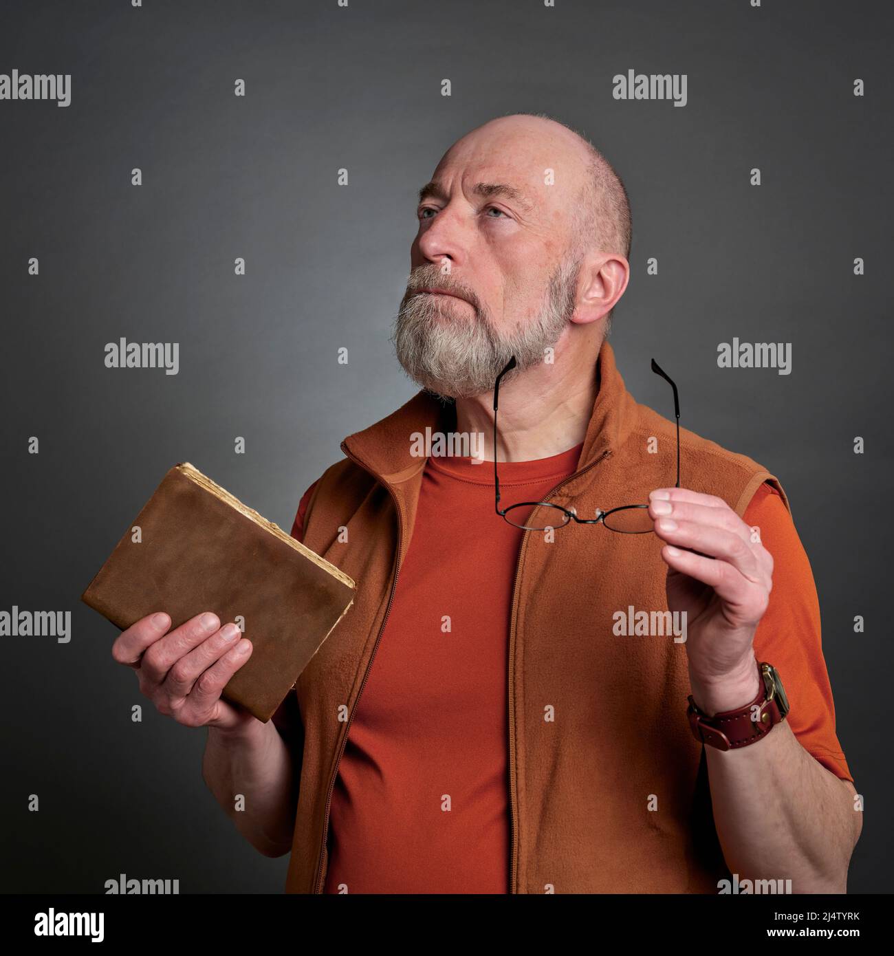 ritratto casual di un anziano barbuto con un vecchio libro e occhiali rotondi, pensiero e contemplazione concetto Foto Stock