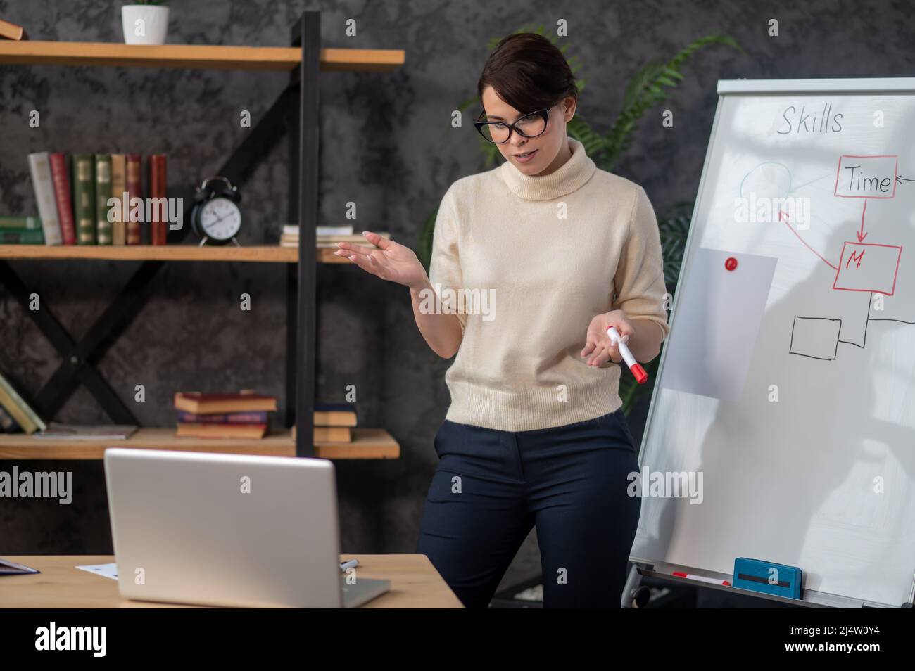 Una tutor femminile in piedi vicino alla lavagna a fogli mobili e materiale di presentazione Foto Stock