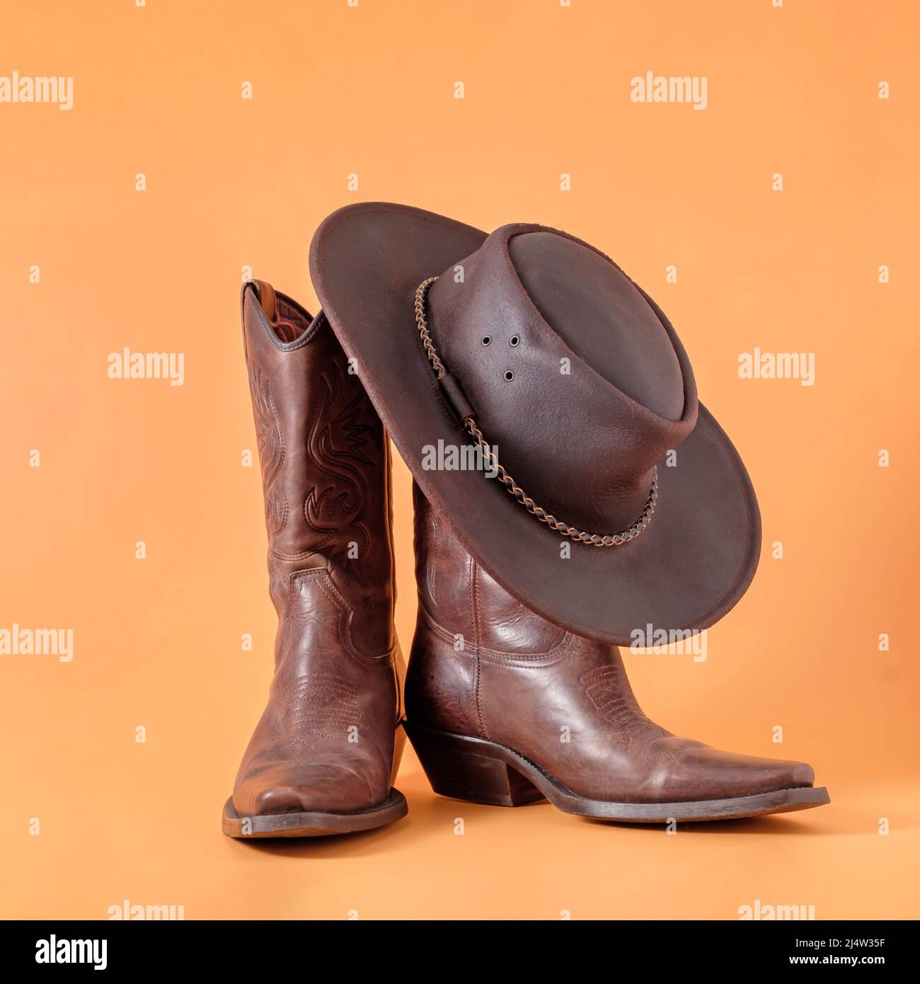 Due eleganti stivali classici e un cappellino stetson in pelle su sfondo argilloso arancione. Ranger concetto cowboy su un ranch in america usa texas Foto stock Alamy