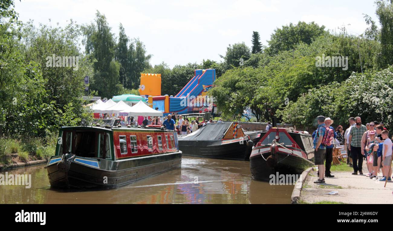 Una barca a noleggio sul canale si sposta attraverso il festival del folclore e della barca di Middlewich, sul canale Trent e Mersey in un fine settimana soleggiato nel giugno 2017 Foto Stock