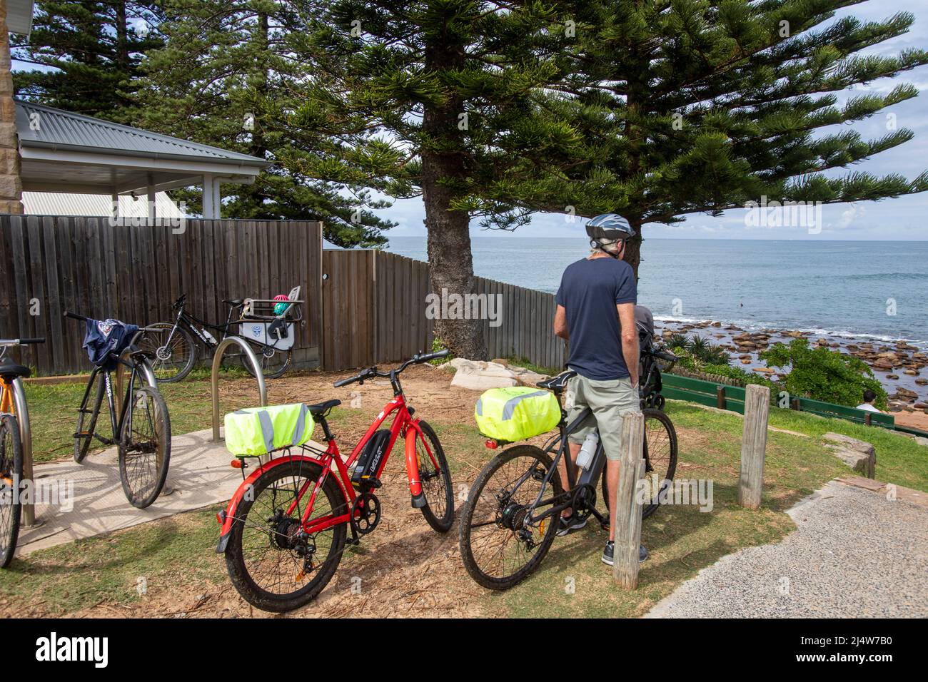 Uomo di mezza età a Sydney seduto a cavalcare la sua bicicletta elettrica e si affaccia sulla spiaggia di Avalon a Sydney, NSW, Australia Foto Stock