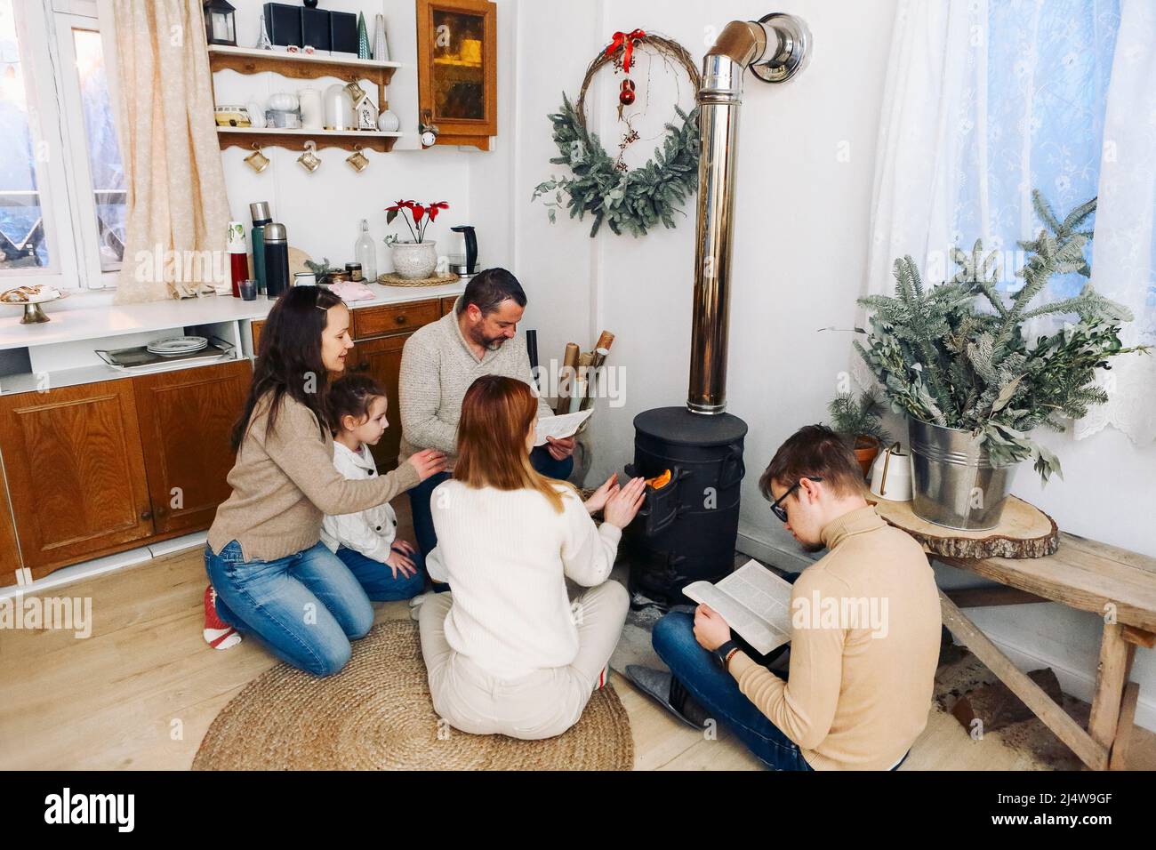 Grande famiglia vestito in maglioni accoglienti seduti vicino al camino nella casa in montagna durnig tempo invernale insieme. Concetto di vacanza e di viaggio Foto Stock