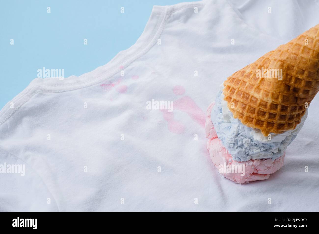 primo piano gelato sporco su abiti bianchi su sfondo blu. vista dall'alto. colorazione quotidiana e concetto di pulizia Foto Stock