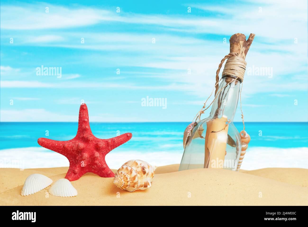 Stella, conchiglie e un messaggio in una bottiglia sulla sabbia della spiaggia. Concetto di composizione di viaggio tropicale estivo Foto Stock