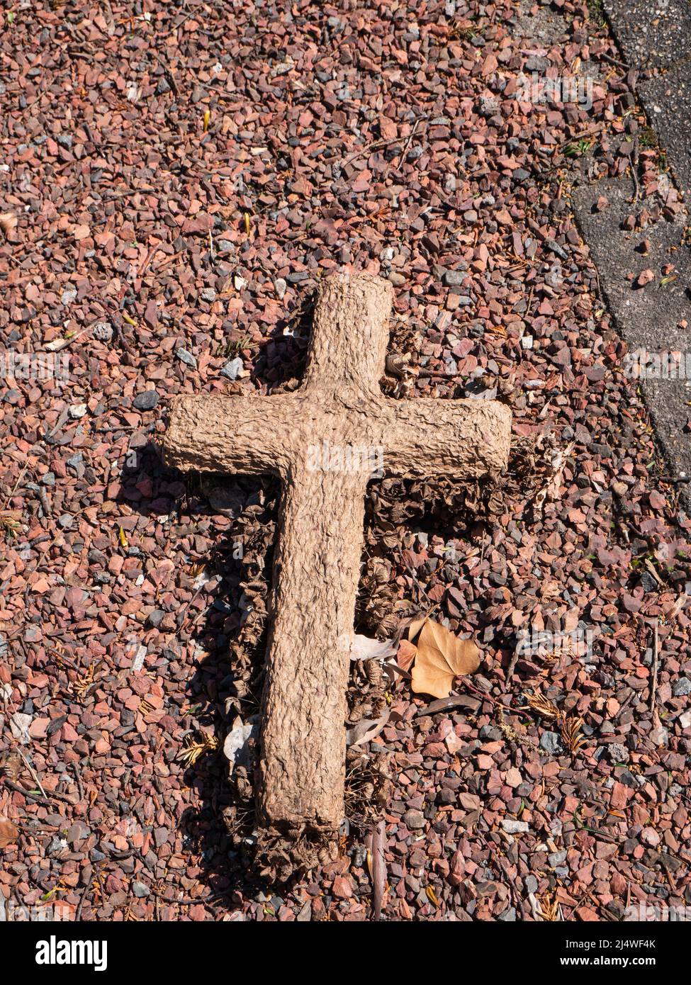 Croce di legno giace sul terreno su ciottoli rossi Foto Stock