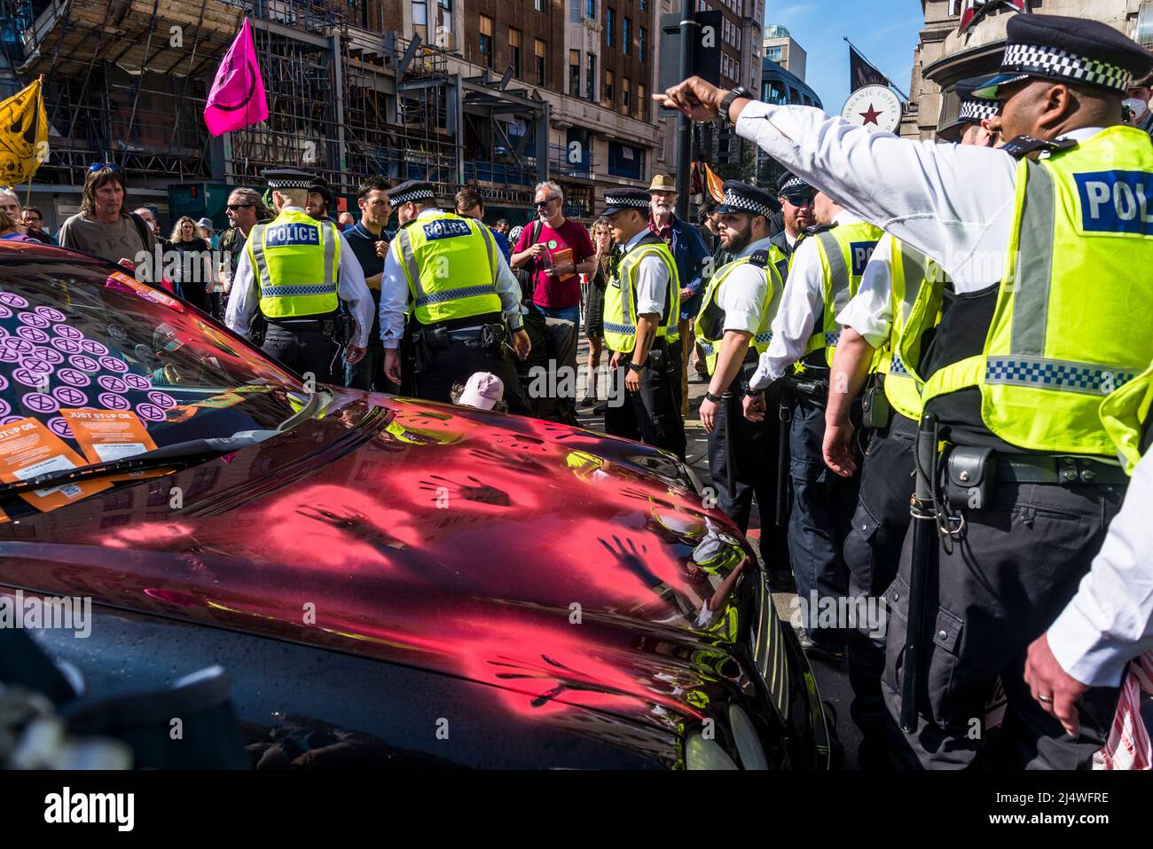 La polizia arriva all'auto bloccata con le impronte di vernice rossa a non saremo spettatori, una protesta della ribellione di estinzione che combatte per la giustizia climatica, Foto Stock