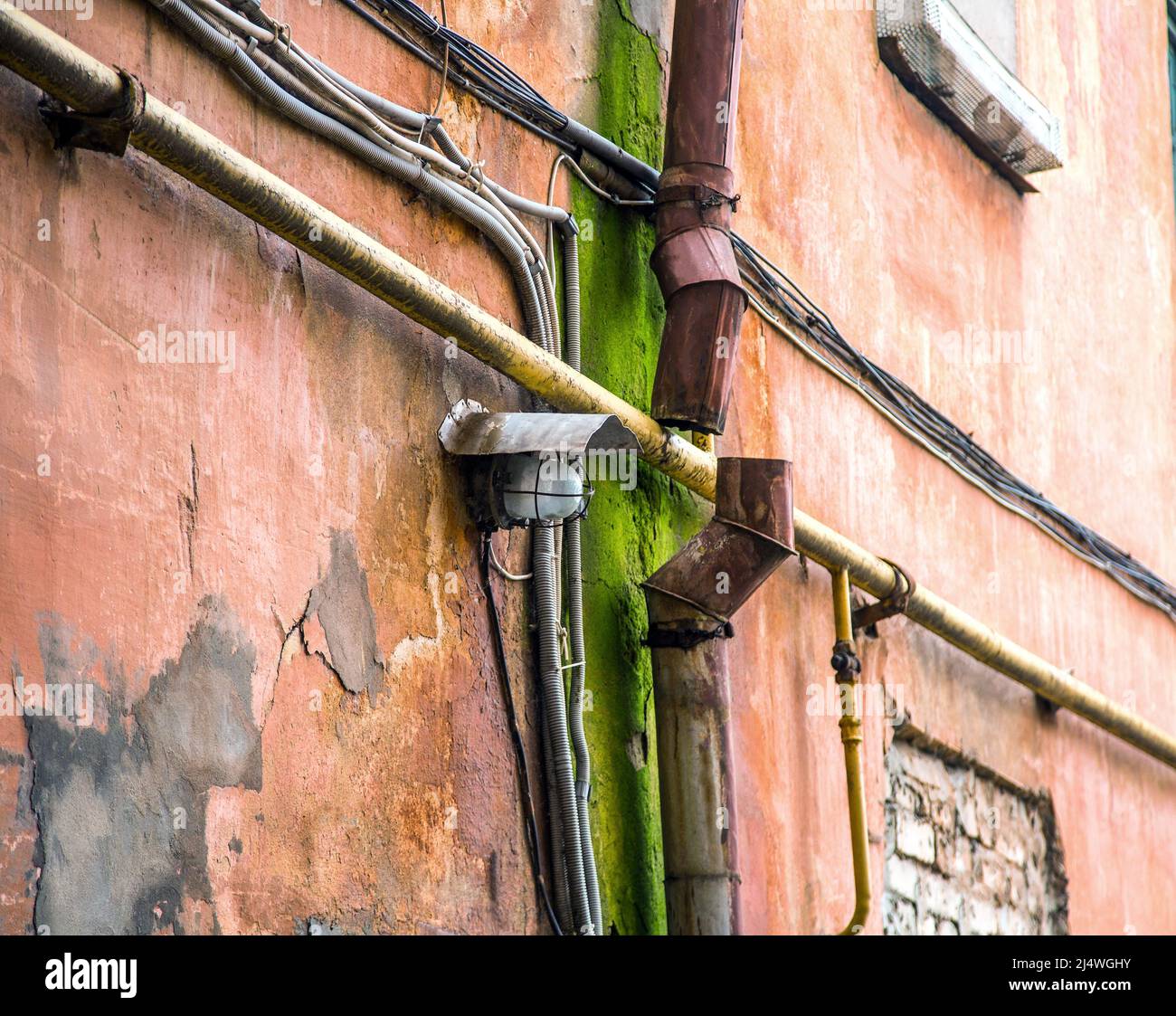 Immagine di una lampada su una vecchia parete vicino ad un tubo di drenaggio arrugginito Foto Stock