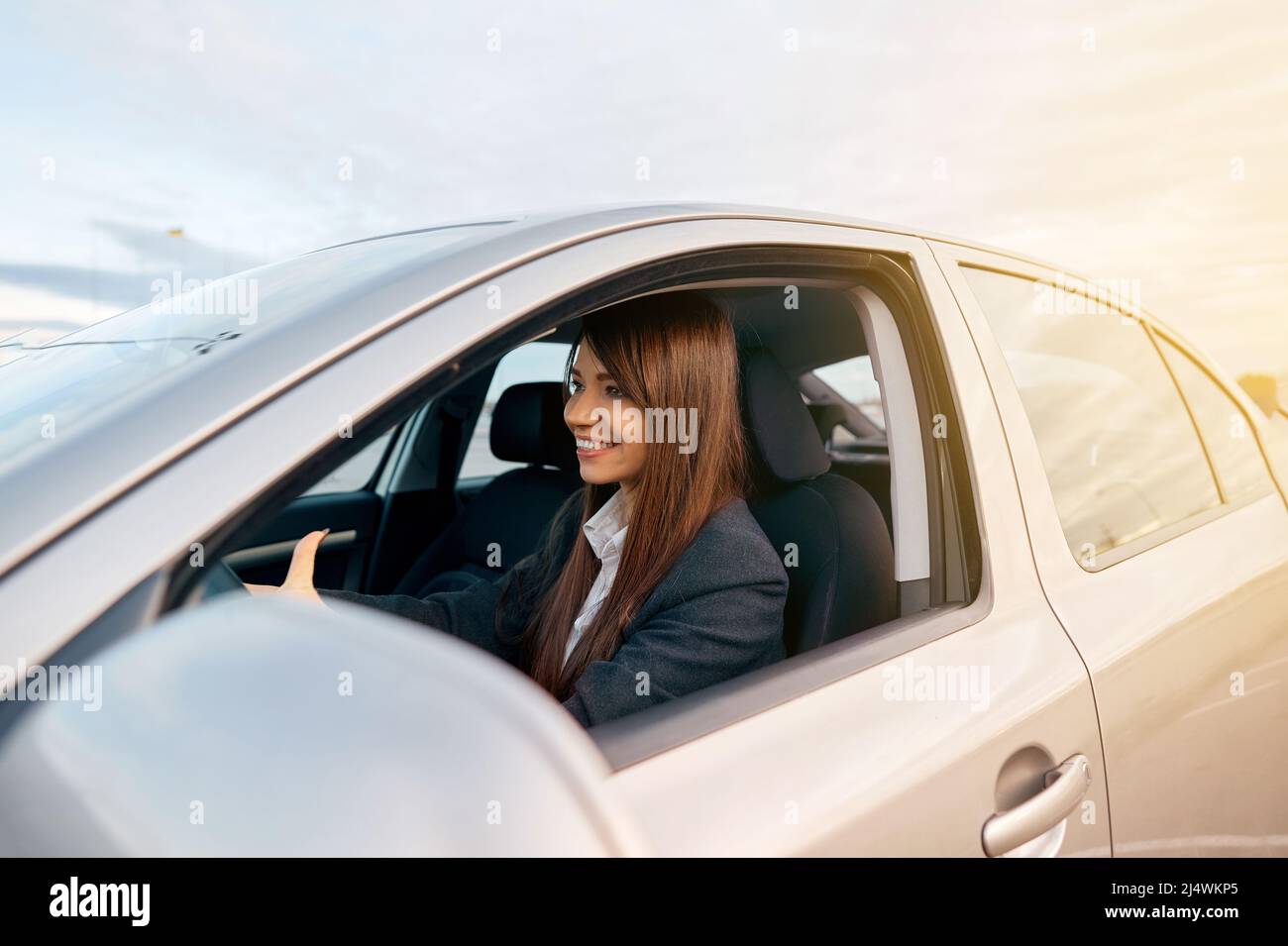 Bella giovane donna sorridente felice alla guida della sua nuova auto. Foto Stock