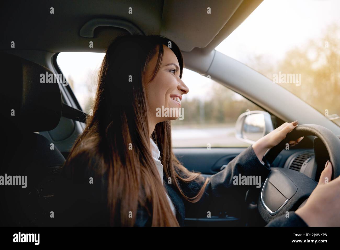 Bella giovane donna sorridente felice alla guida della sua nuova auto Foto Stock