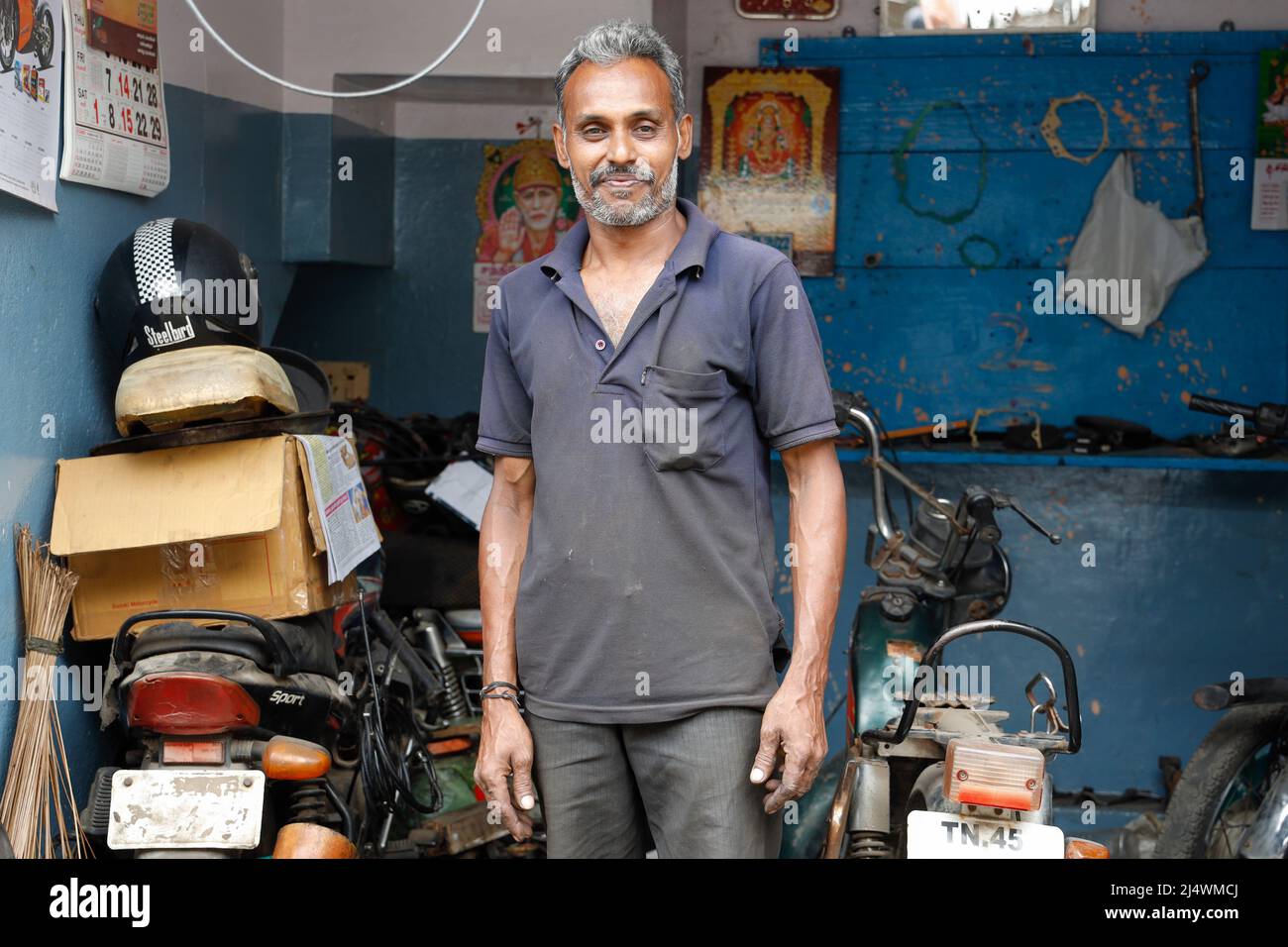 Meccanico del motociclo che posa nella sua officina inTrichy, Tamil Nadu, India Foto Stock
