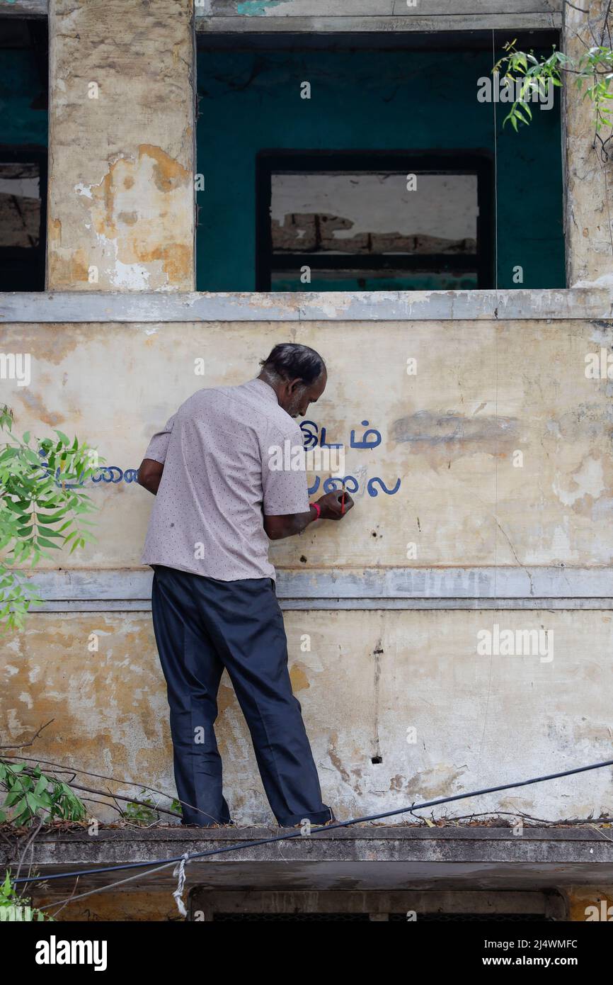 Uomo che dipinge un segno non per la vendita sulla facciata di una casa dilapidata a Trichy, Tamil Nadu, India Foto Stock