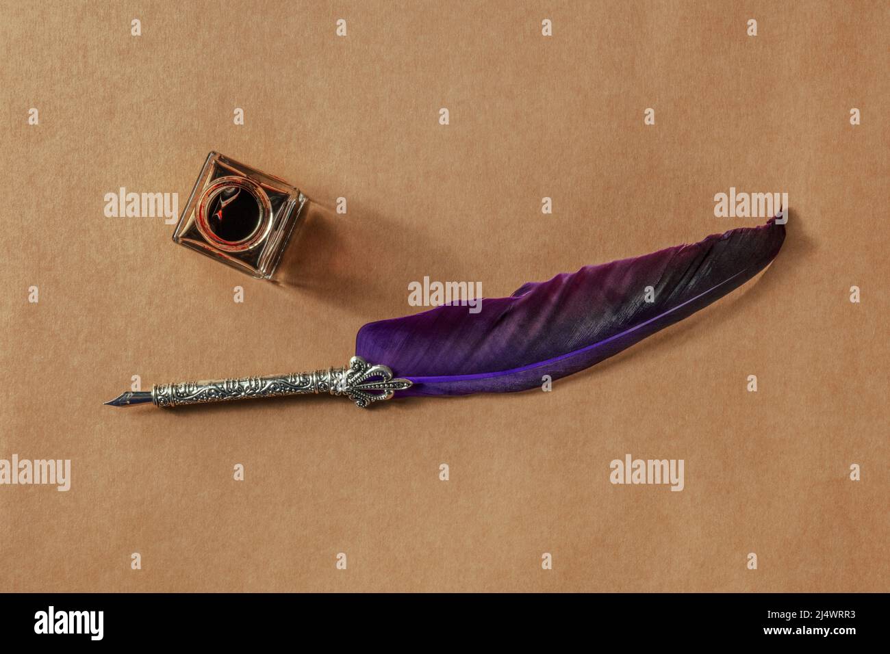 Una penna di quill con un vecchio inkwell, getto di getto piano sopra la carta marrone, il concetto di scrittura Foto Stock
