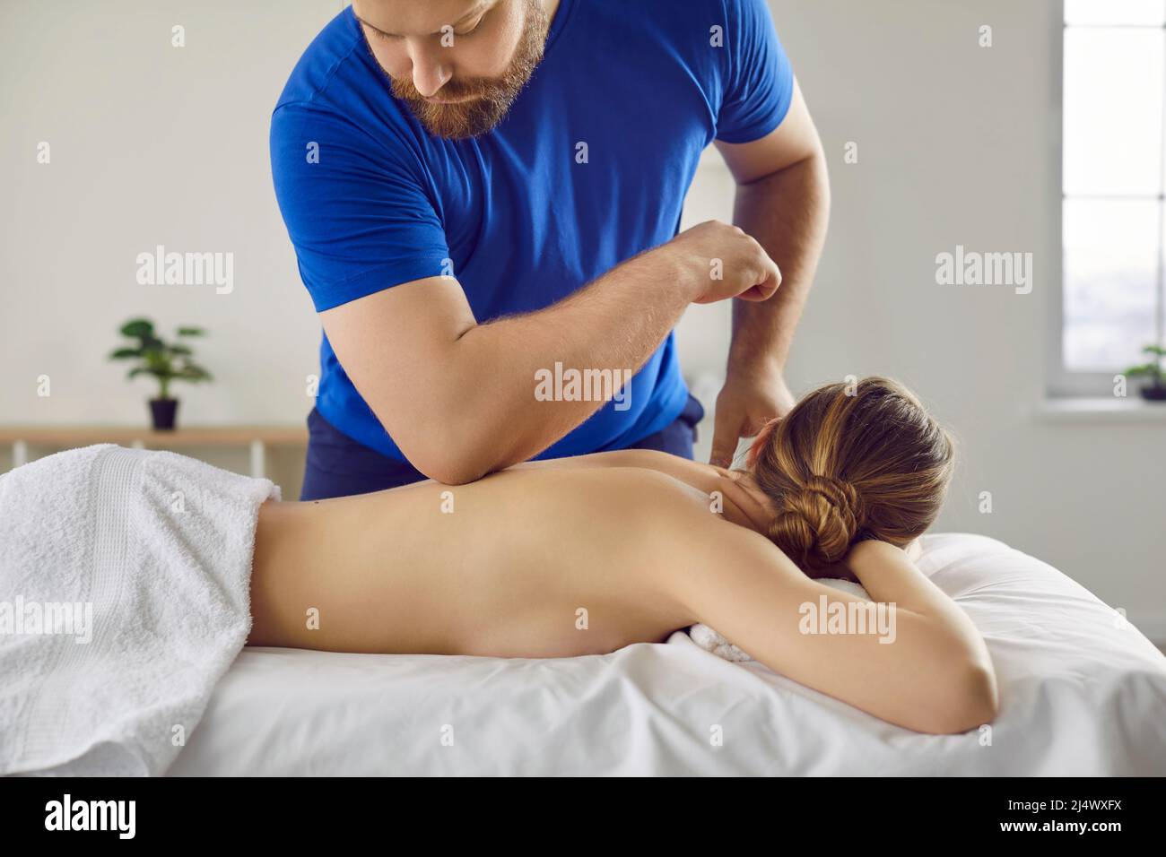 Il massaggiatore utilizza il gomito per massaggiare la schiena della paziente durante il trattamento con shiatsu Foto Stock