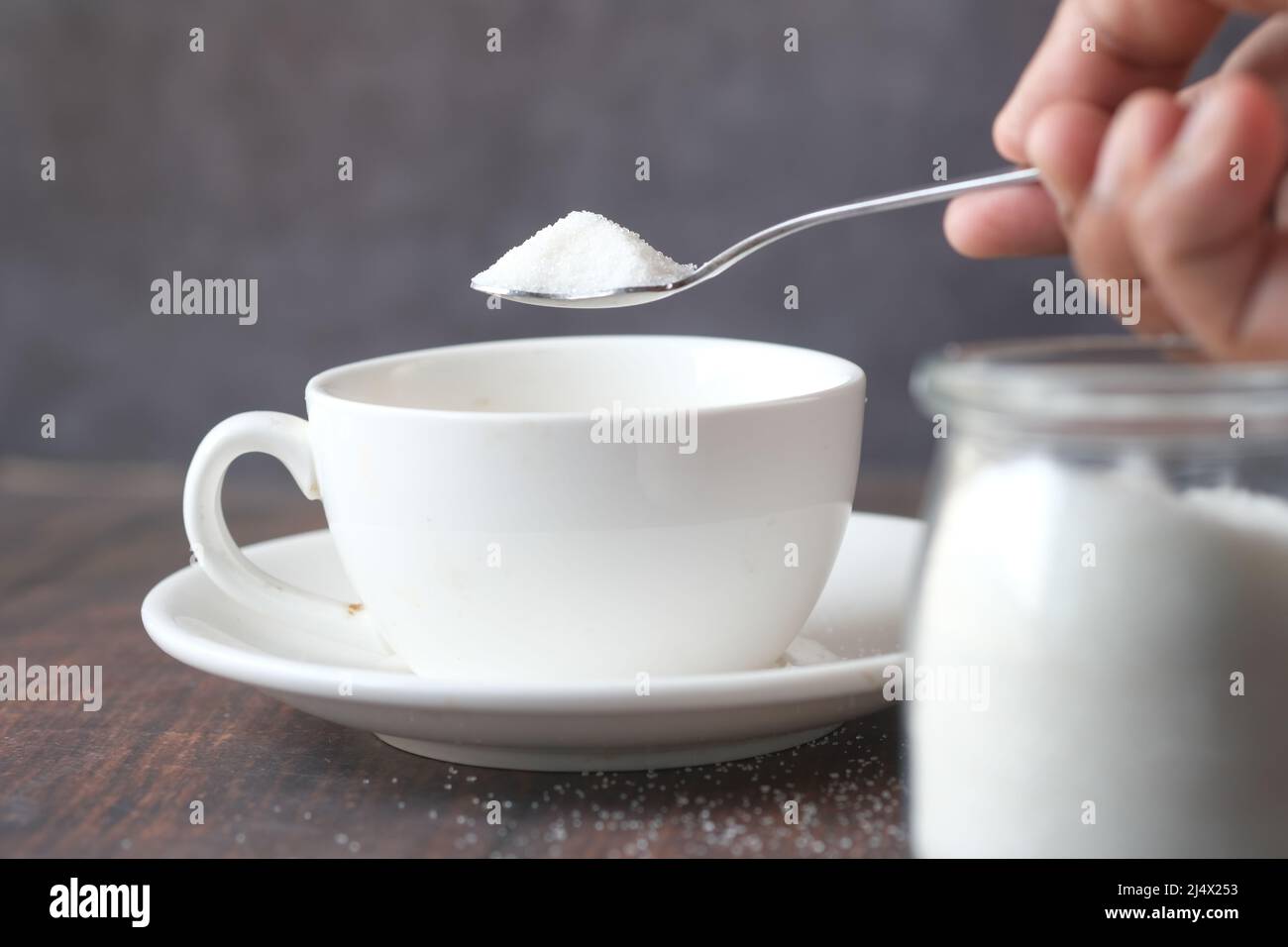 mettere lo zucchero bianco in una tazza da tè Foto Stock