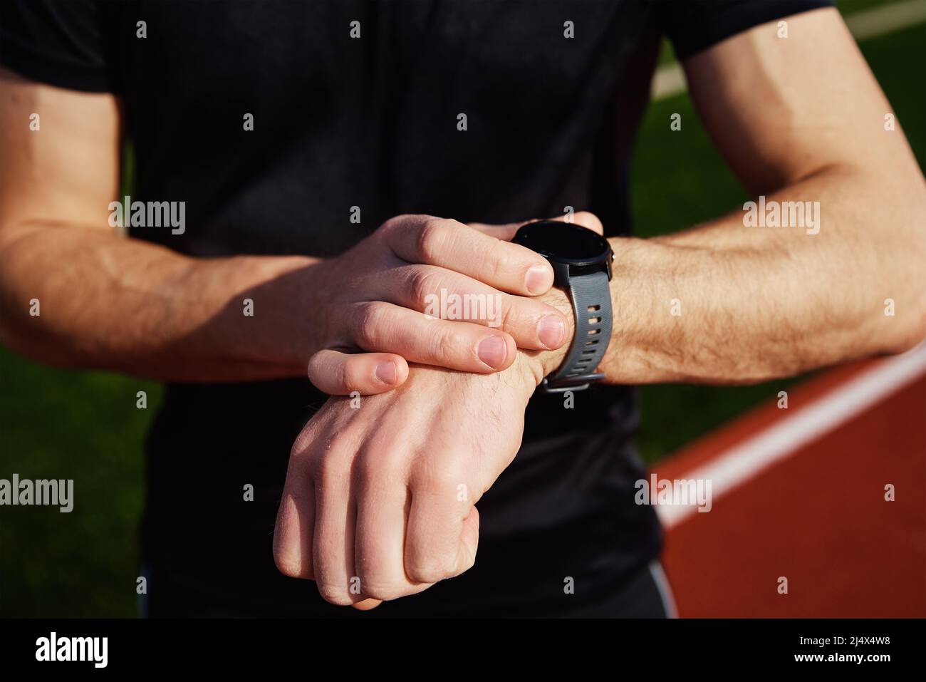 Uomo che controlla l'orologio di idoneità dopo gli esercizi alla cremagliera dello stadio Foto Stock