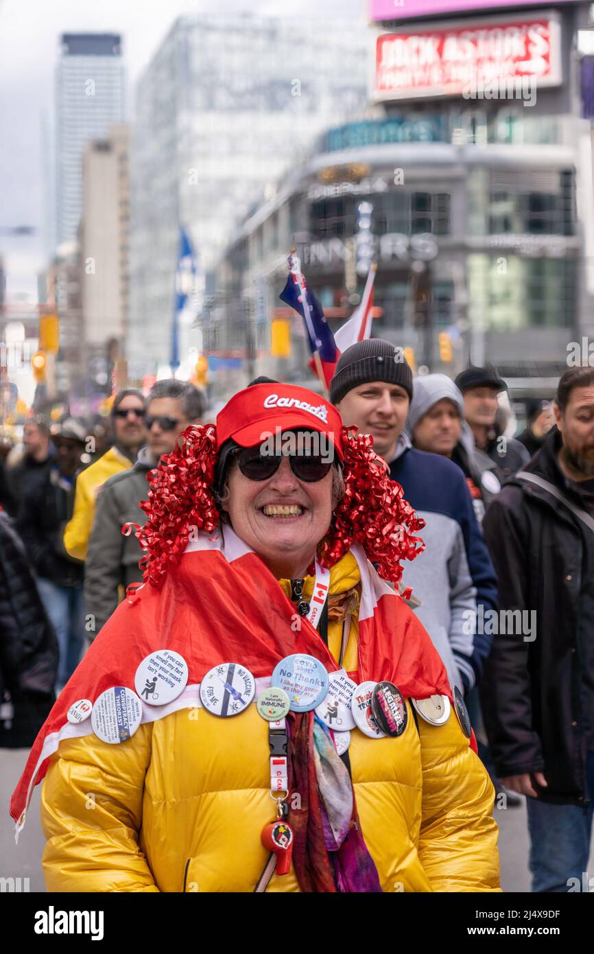 Una donna canadese sorride indossando spilli antivaccine nel petto. Fa parte di una marcia di protesta nel centro della città (Yonge-Dundas Square distric Foto Stock