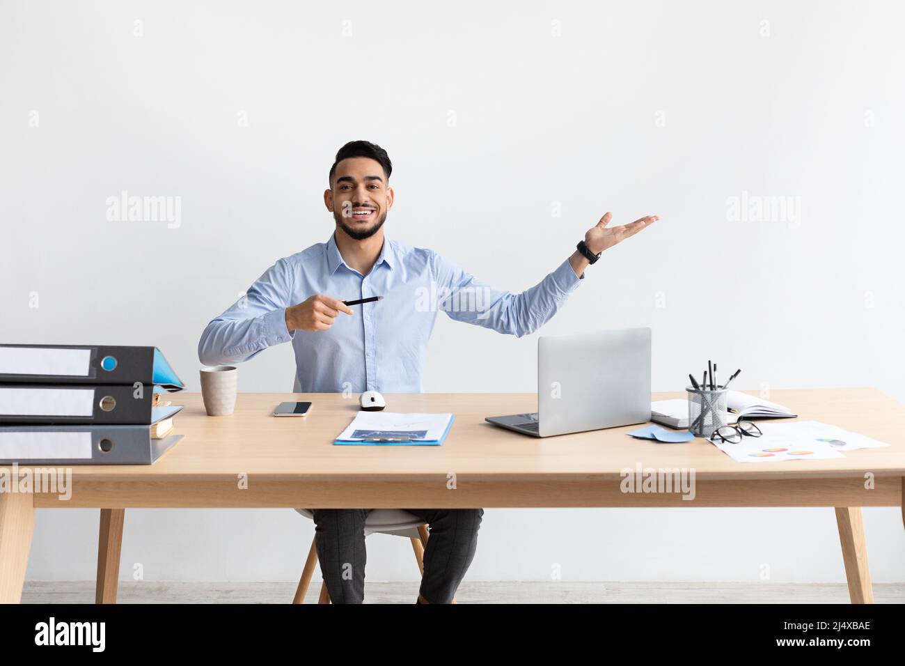 Happy Bearded Man che punta da parte seduto sul posto di lavoro Foto Stock
