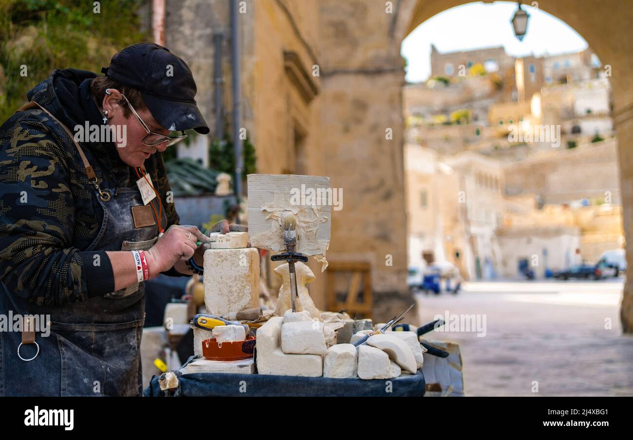 una donna artigiana lavora sulla pietra creando una statua con i suoi strumenti e materiali Foto Stock