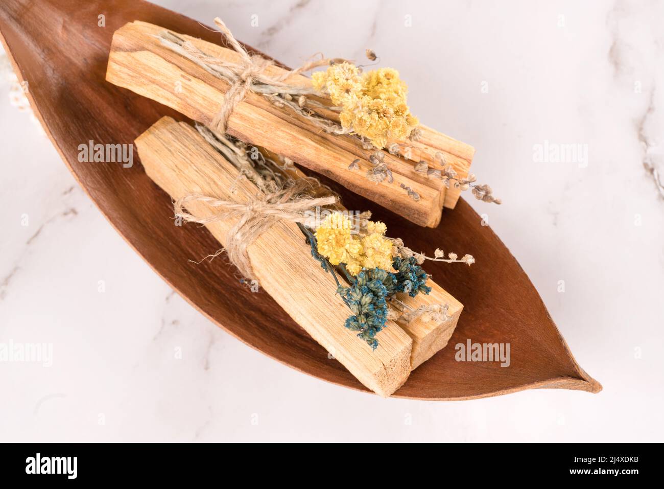 Bastoni Palo santo con mazzi di fiori secchi su sfondo di tavolo di marmo bianco. Composizione piatta con bastoncini di legno santo per la meditazione e la spiritua Foto Stock