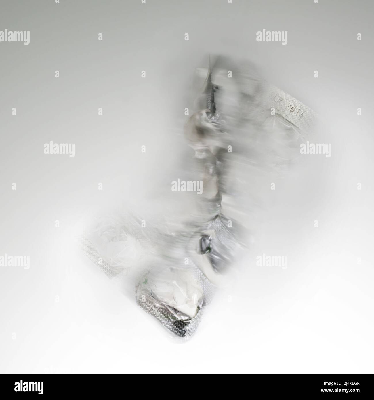 Sfuocatura astratta del movimento di una confezione blister per pillole in alluminio e plastica su sfondo grigio chiaro, concetto per la salute e tossicodipendenza Foto Stock