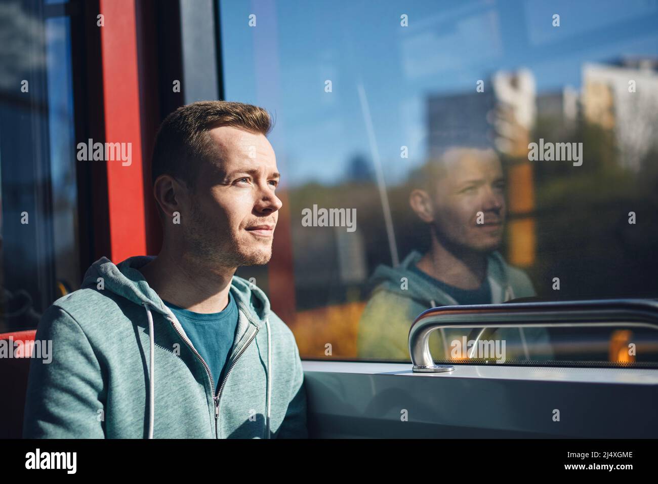 Uomo che passa in tram. Passeggero adulto che guarda fuori dalla finestra del treno dei mezzi pubblici. Foto Stock