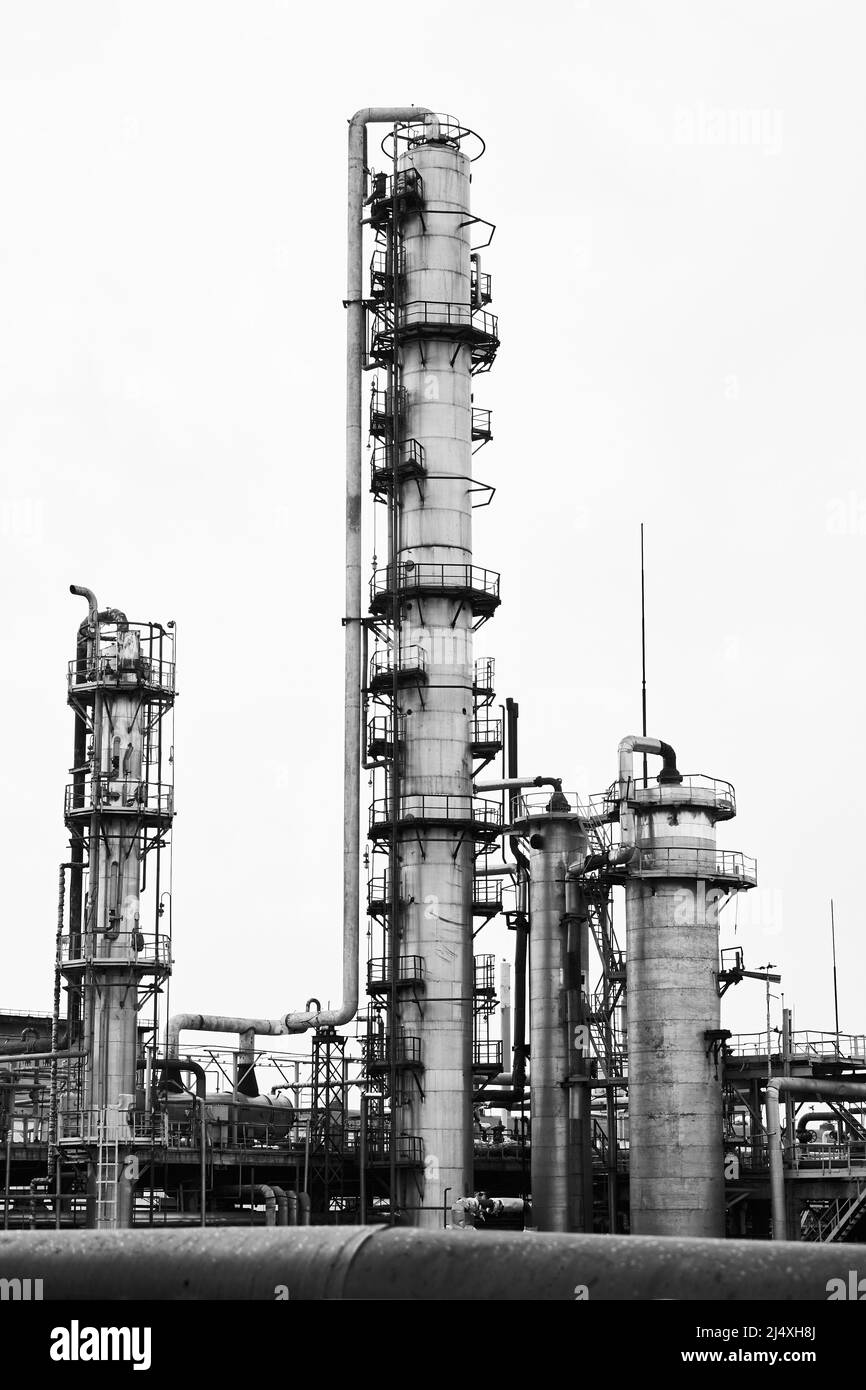 Vecchia distillazione del metanolo rettifica colonne di raffineria torri e reattori sotto il cielo grigio in impresa di impianti chimici. Bianco e nero industriale BW Foto Stock