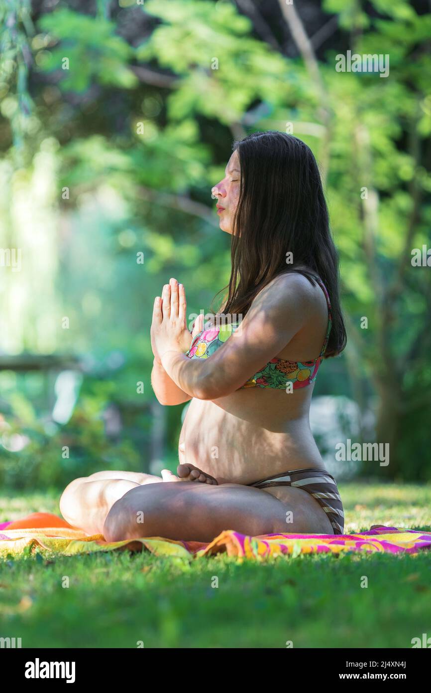 giovane donna incinta che fa yoga all'aperto Foto Stock