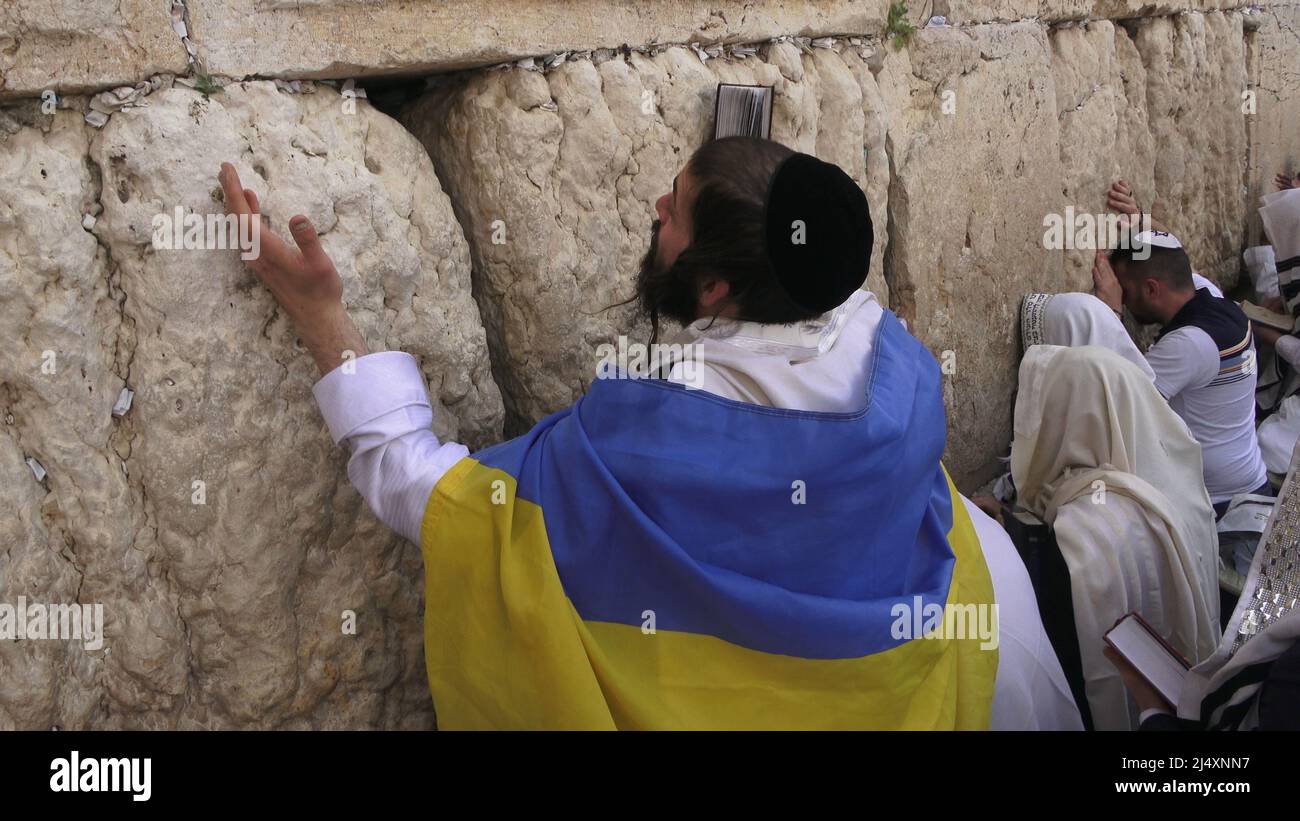 Un adoratore ebreo avvolto con la bandiera Ucraina e la preghiera Talit Shawl prega come ebrei religiosi della casta sacerdotale di Cohanim prendere parte alla messa biennale 'Birkat Kohanim' o 'benedizione sacerdotale' nella festa di Pesach (Pasqua) al Kotel a Gerusalemme, Israele. Foto Stock