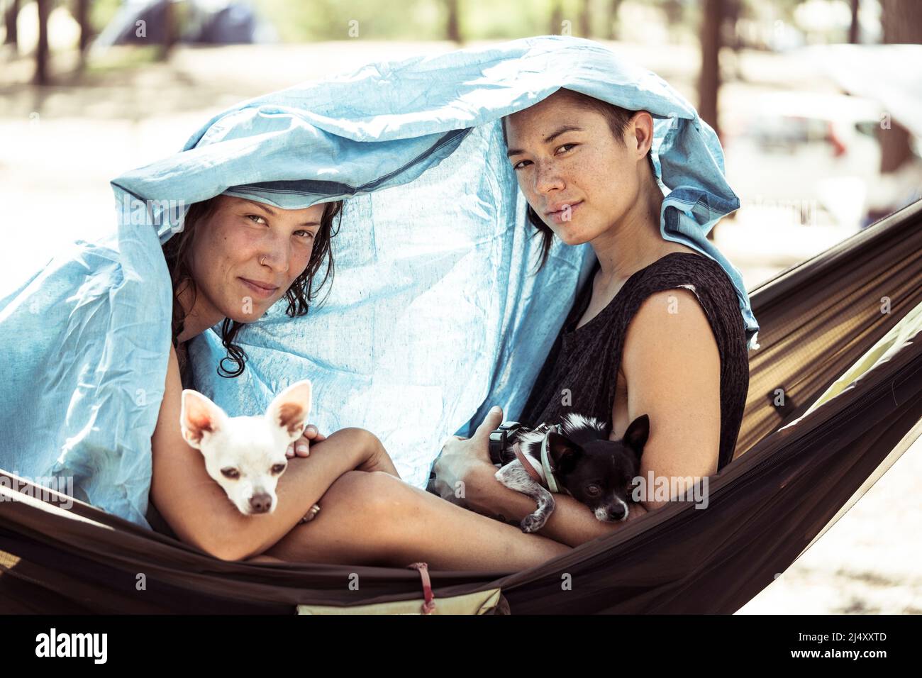 Due donne in amaca riparo dal sole con cani in Portogallo Foto Stock