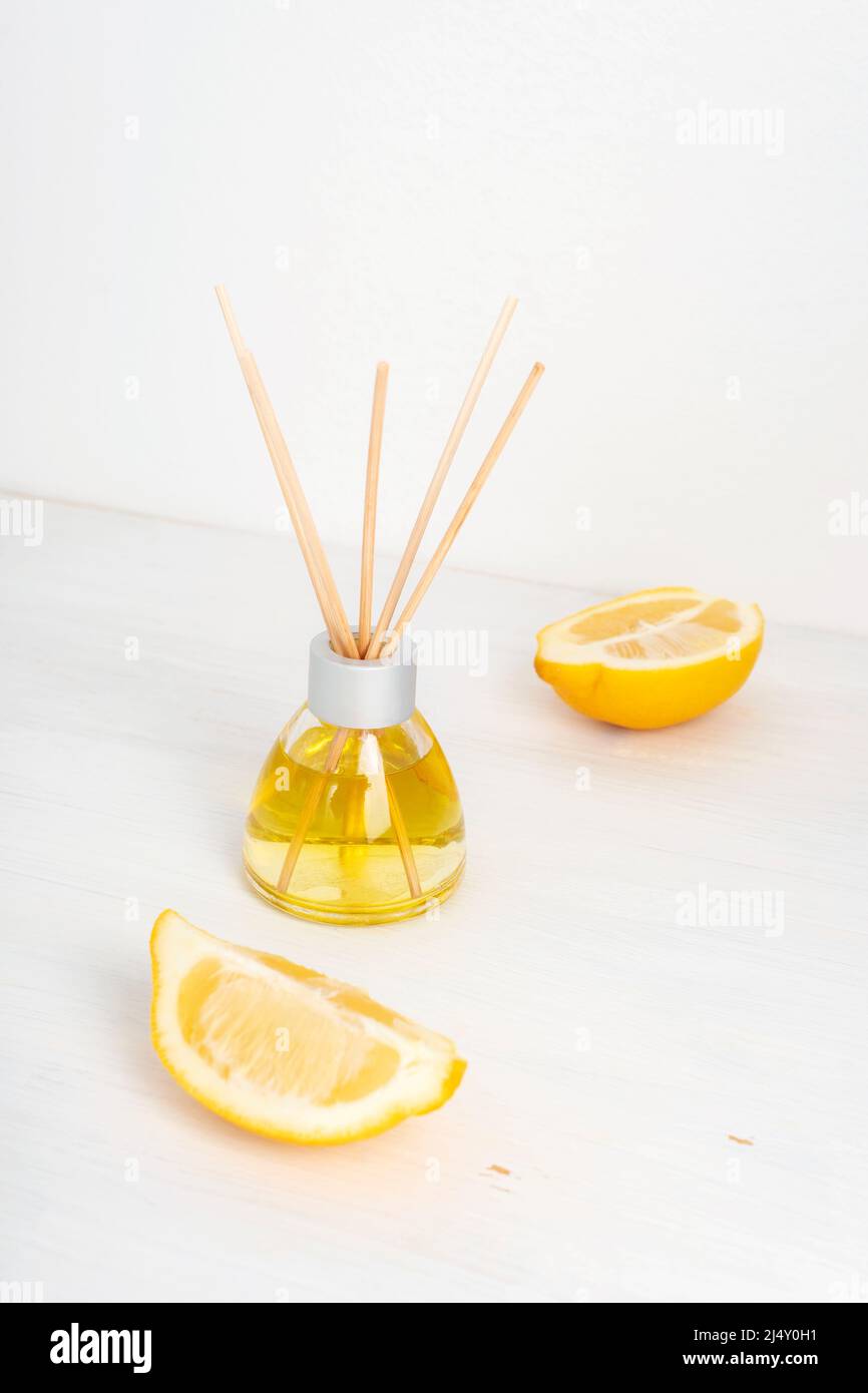 Bottiglia di vetro con diffusore di aroma e fette di limone su sfondo bianco. Messa a fuoco selettiva Foto Stock