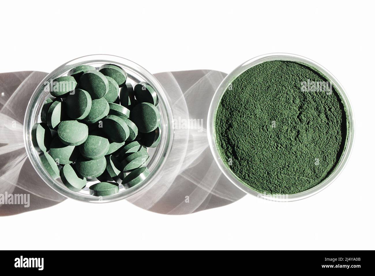 additivi naturali e superfood. polvere di alghe spirulina verde e pillole in ciotole di vetro su sfondo bianco. concetto di stile di vita sano. cibo biologico Foto Stock