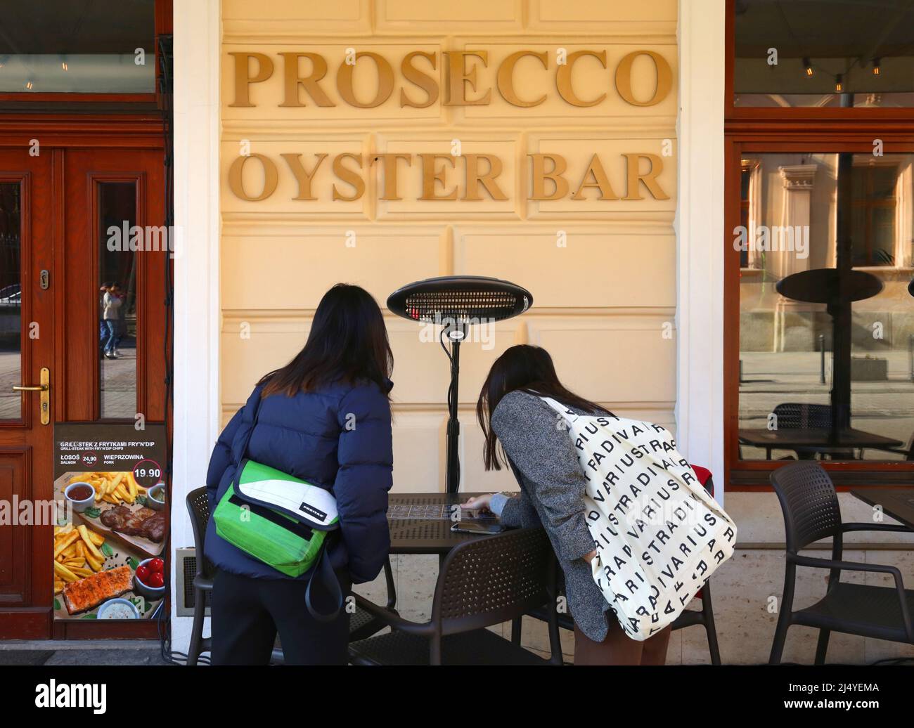 Cracovia. Cracovia. Polonia. Due giovani donne che leggono il menu di fronte al Prosecco Oyster Bar. Foto Stock