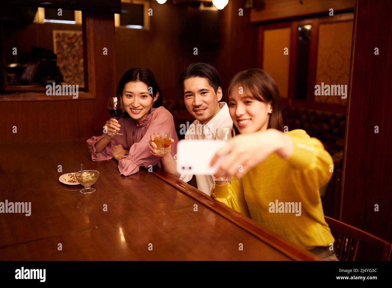 Amici giapponesi che bevono un drink al banco del bar Foto Stock