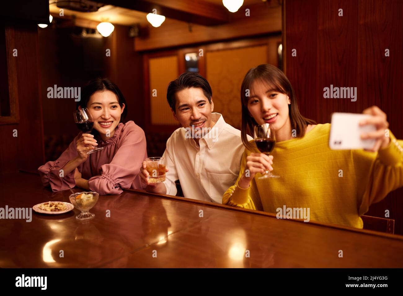 Amici giapponesi che bevono un drink al banco del bar Foto Stock