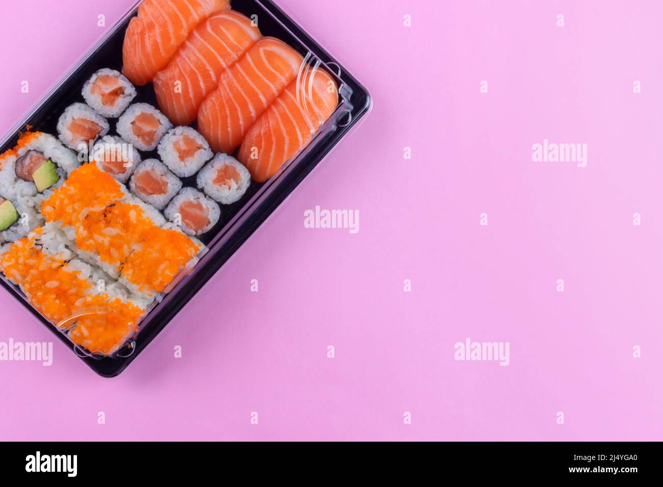 Scatola per la consegna del sushi al salmone con maki e california su sfondo rosa Foto Stock