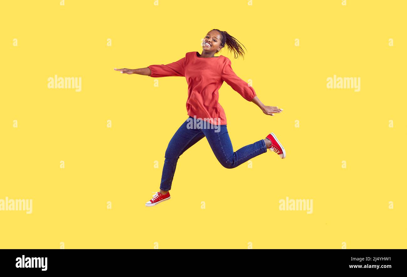 Donna afro-americana felice in abiti casual saltando isolato su sfondo giallo Foto Stock
