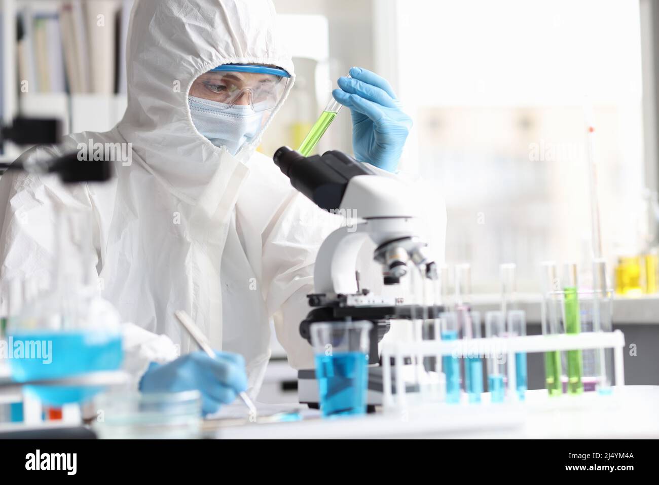 Lo scienziato in tuta protettiva studia liquidi tossici velenosi in laboratorio Foto Stock