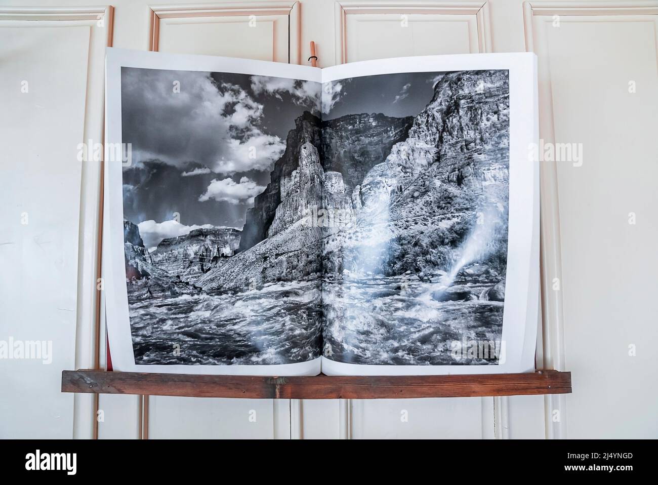 Libro aperto con foto di mare contro montagna disposti su scaffale Foto Stock
