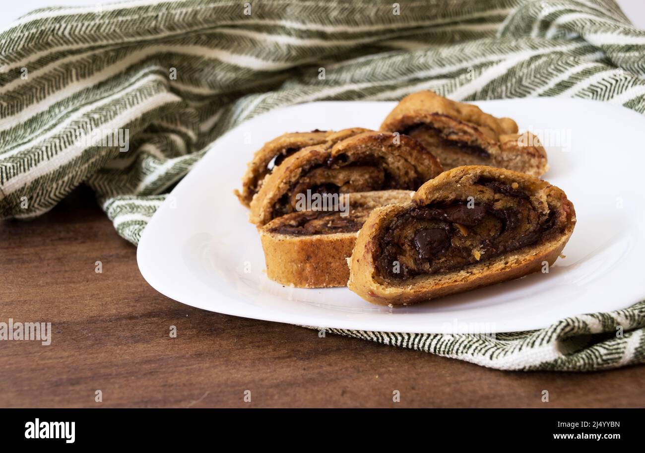 Pane affettato con ripieno di cioccolato dolce all'interno di un piatto su una tovaglia verde a strisce Foto Stock